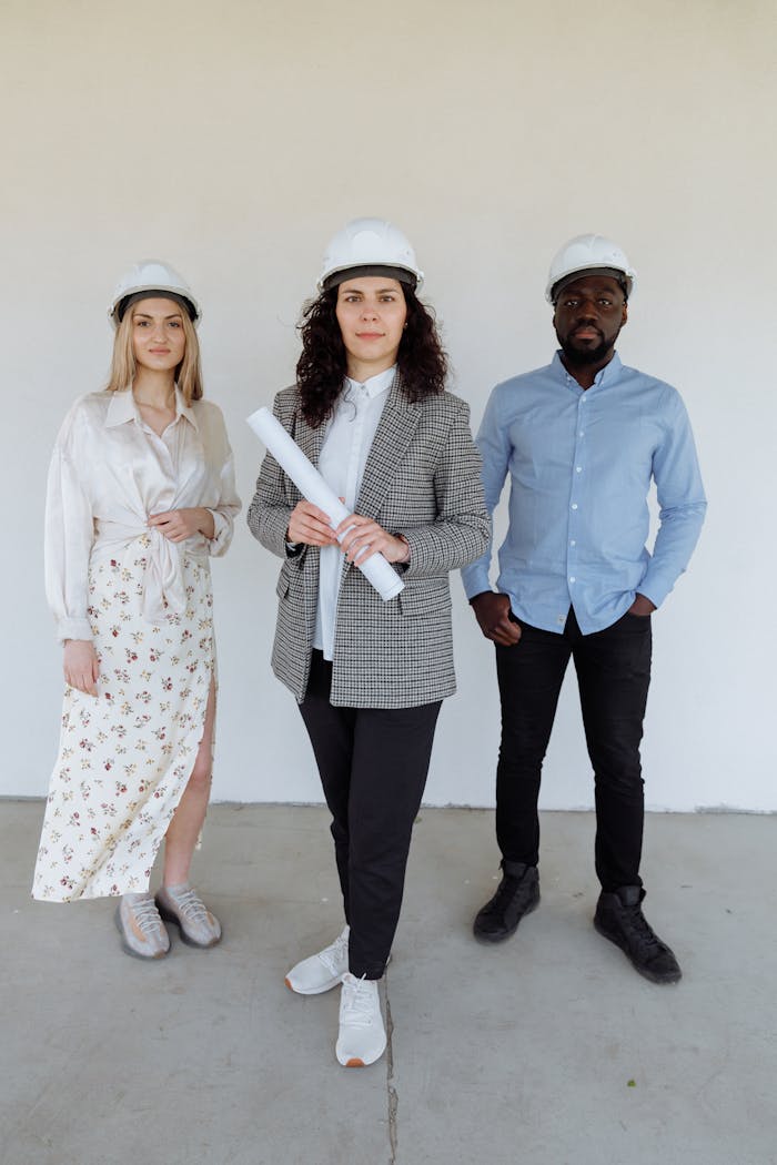our-services-3 Diverse group of architects in white helmets discussing a construction project indoors.