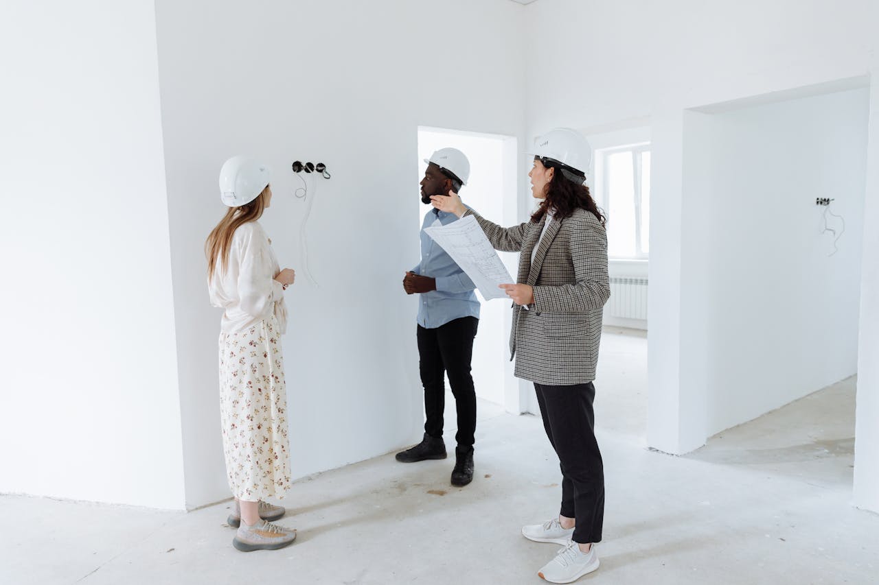 gallery-2 Three professionals discuss design plans inside a new house wearing hard hats.